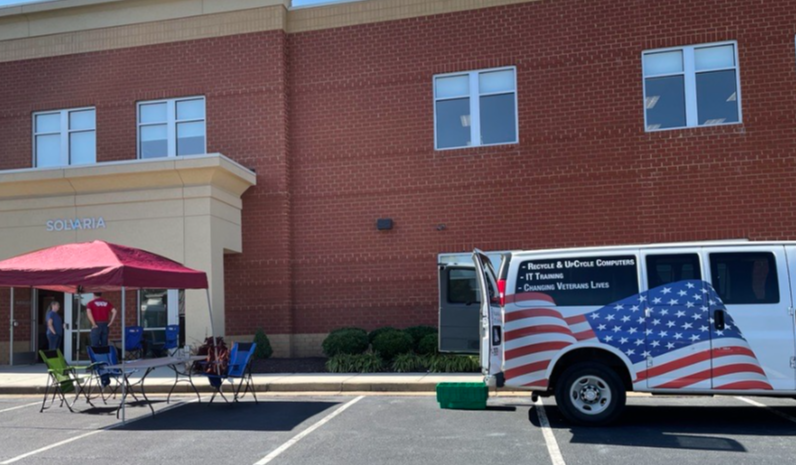 A van displaying American flag parked by a building.
