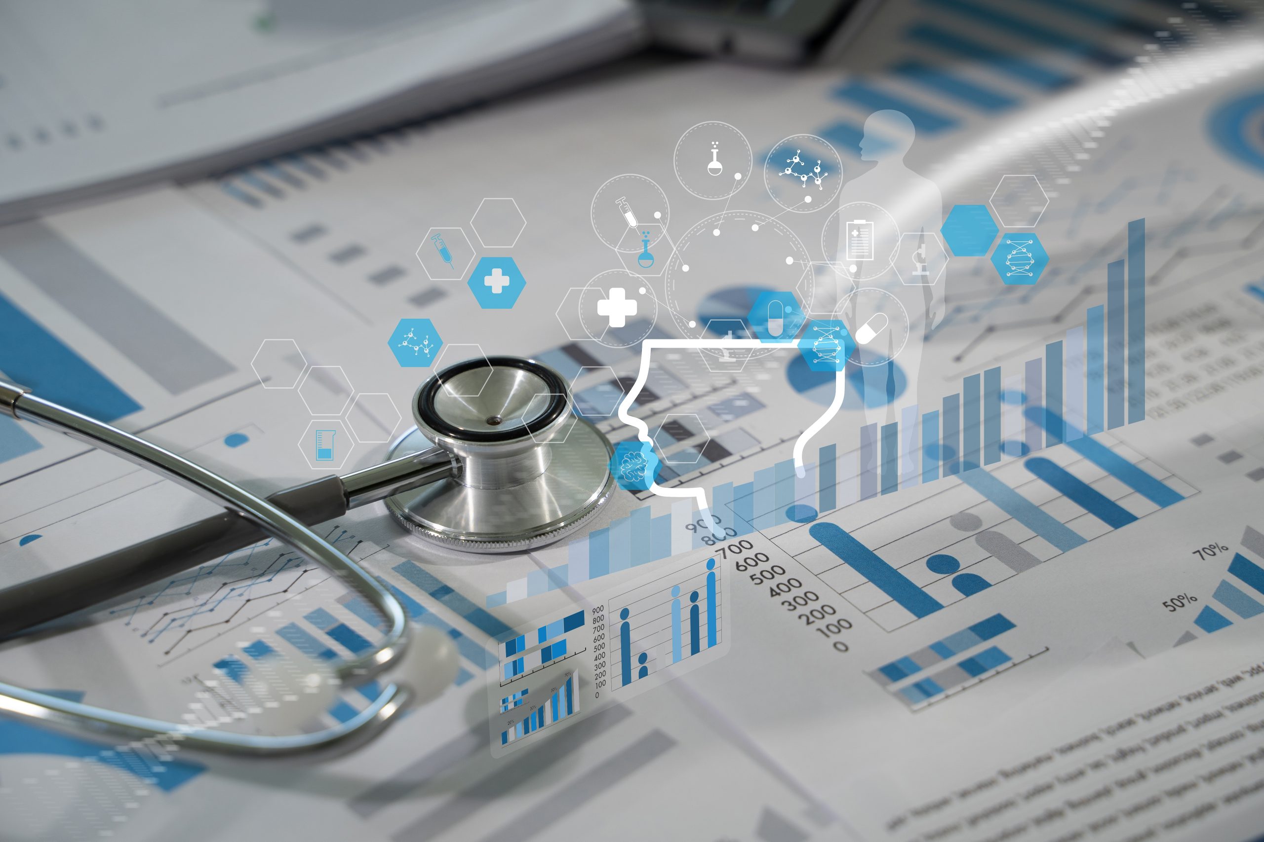 A stethoscope resting on medical charts with blue graphs and data. Digital health icons and a human profile outline overlay the image, symbolizing medical technology and data analysis.