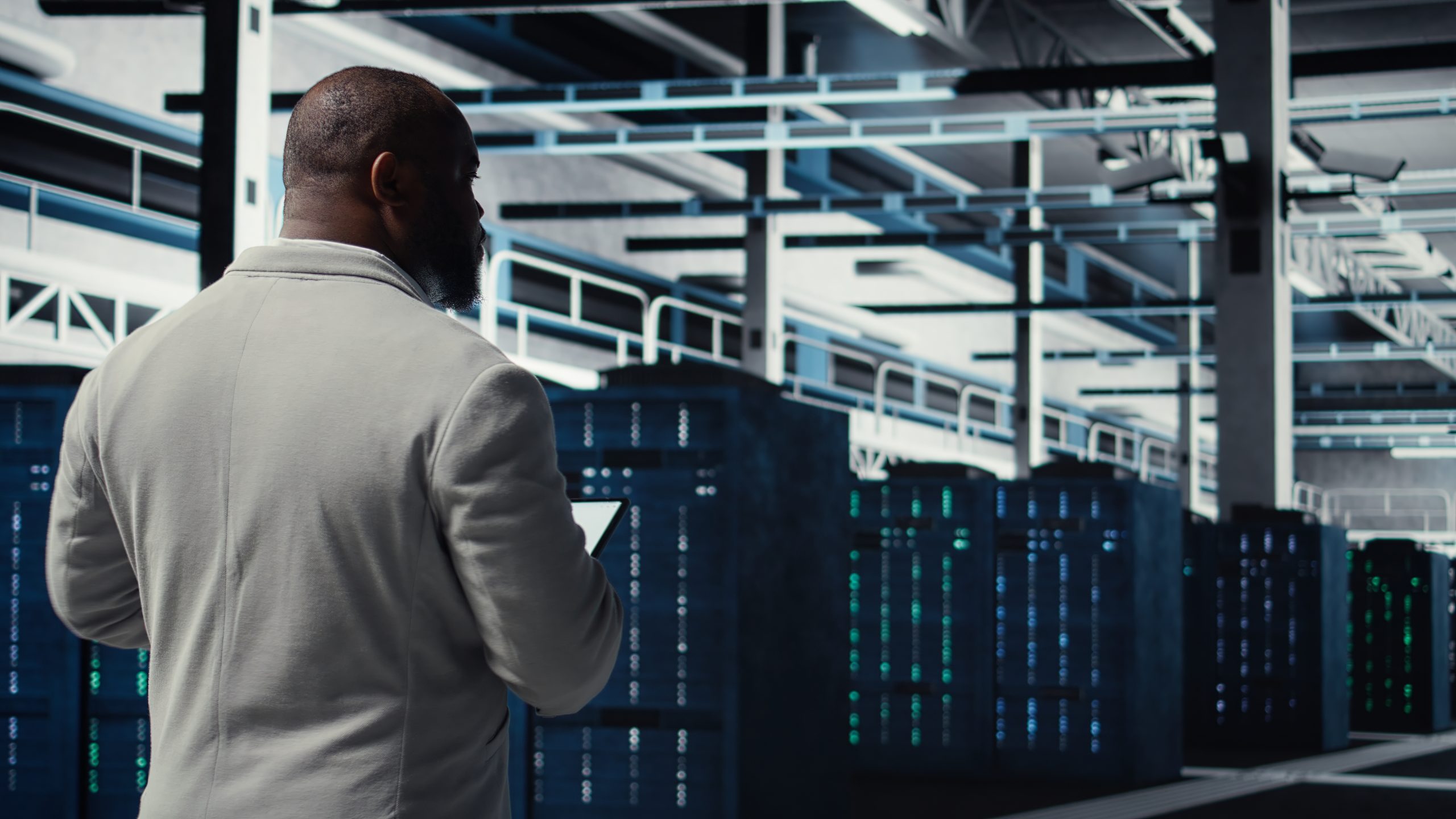 A man in a white jacket stands in a modern server room, facing rows of illuminated server racks and holding a tablet, suggesting he is monitoring or managing Exadata systems and Oracle Cloud managed services.