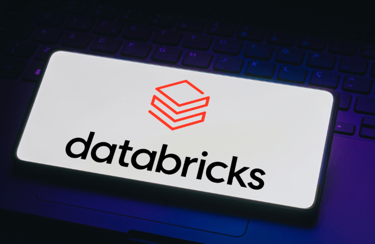 A smartphone displays the Databricks logo and name on its screen, placed on a dark keyboard background. The logo consists of red geometric shapes above the word “databricks” in bold black letters.