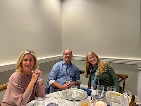 Three people enjoying a conversation over wine at a table.