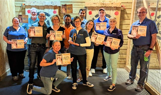 A diverse group of individuals proudly displaying certificates in front of a wall.
